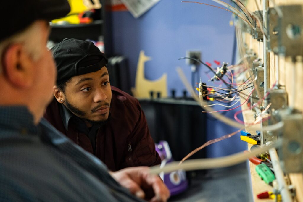 Student in Centura College's electrical apprenticeship program learning hands-on wiring techniques with an instructor in a classroom lab.